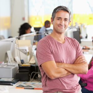 Portrait Of Man Standing In Busy Creative Office.